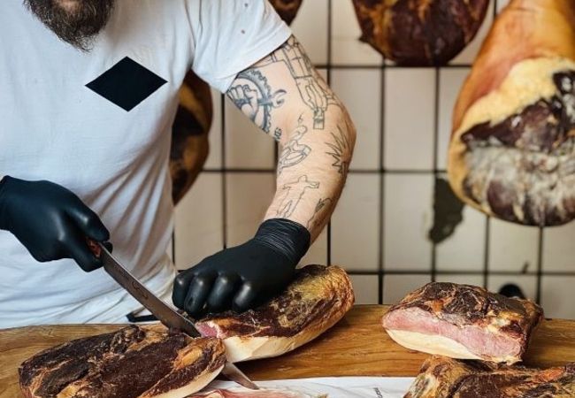 Ein Mitarbeiter schneidet Fleisch - Fleischerei Münch